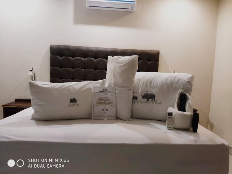 A bedroom featuring a dark upholstered headboard and a wall-mounted air conditioning unit.
