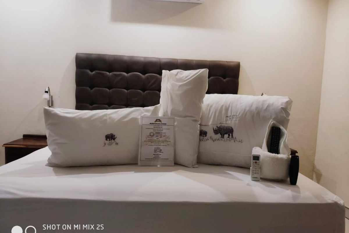 A bedroom featuring a dark upholstered headboard and a wall-mounted air conditioning unit.