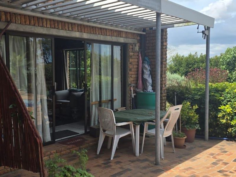 A covered outdoor patio area featuring brick walls, paved flooring, and sliding glass doors providing access to the interior living space.