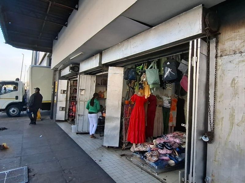 Street-level view of a commercial shop front featuring metal security shutters, a protective awning, and direct access from the public pavement.