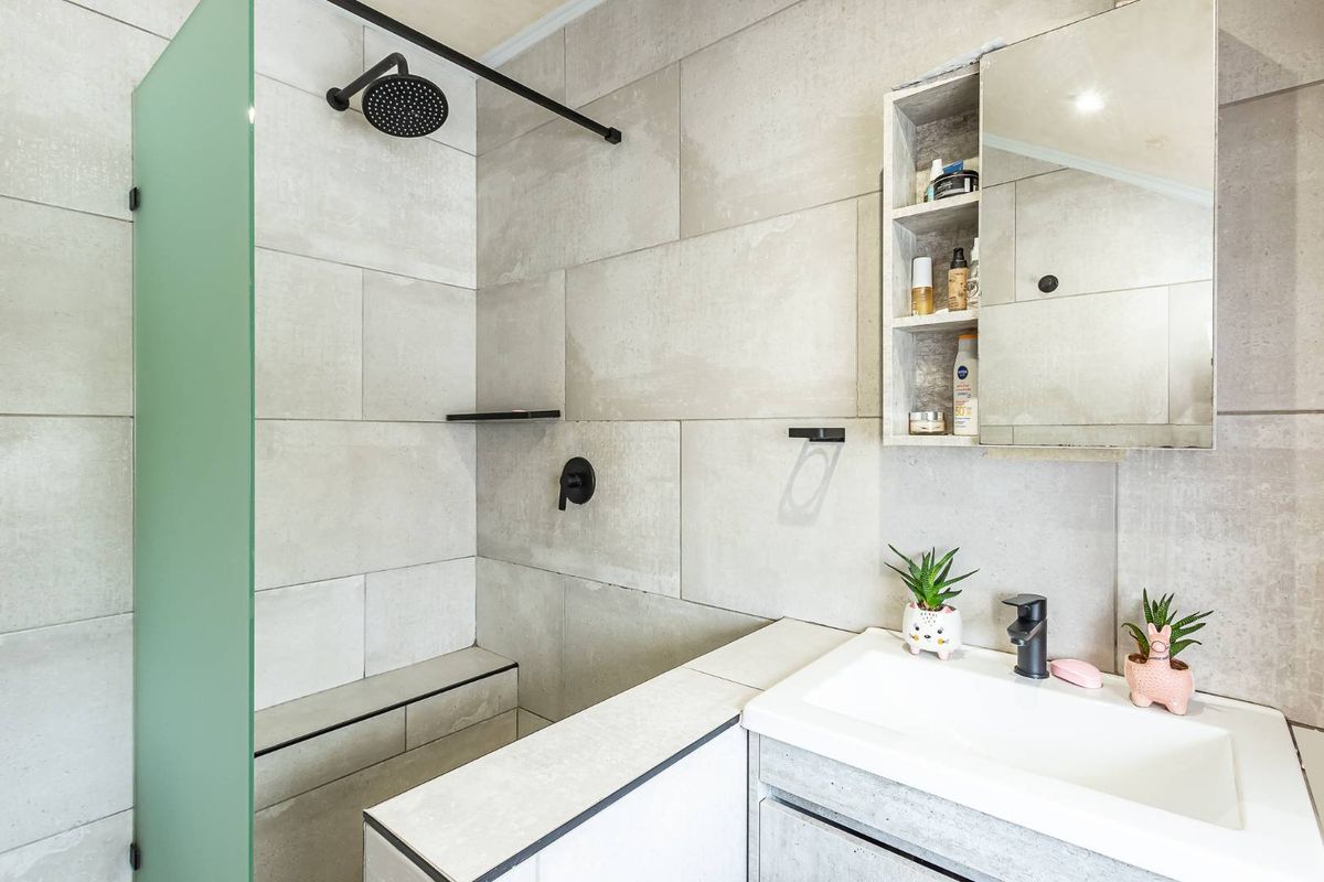 Modern bathroom featuring a walk-in shower with a rain shower head, built-in bench, vanity basin with cabinet, and a mirrored medicine cabinet.