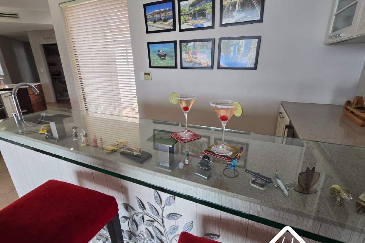 A kitchen breakfast bar featuring a stone countertop, integrated sink, and decorative wall paneling, providing a functional space for casual dining and food preparation.