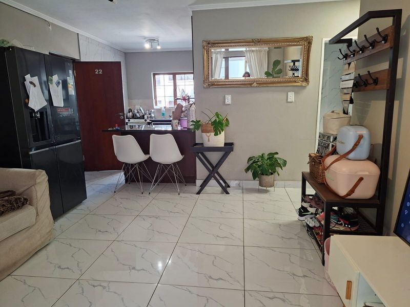 Open-plan living area featuring modern marble-look floor tiles and a functional kitchen breakfast bar, creating a seamless flow between cooking and living spaces.