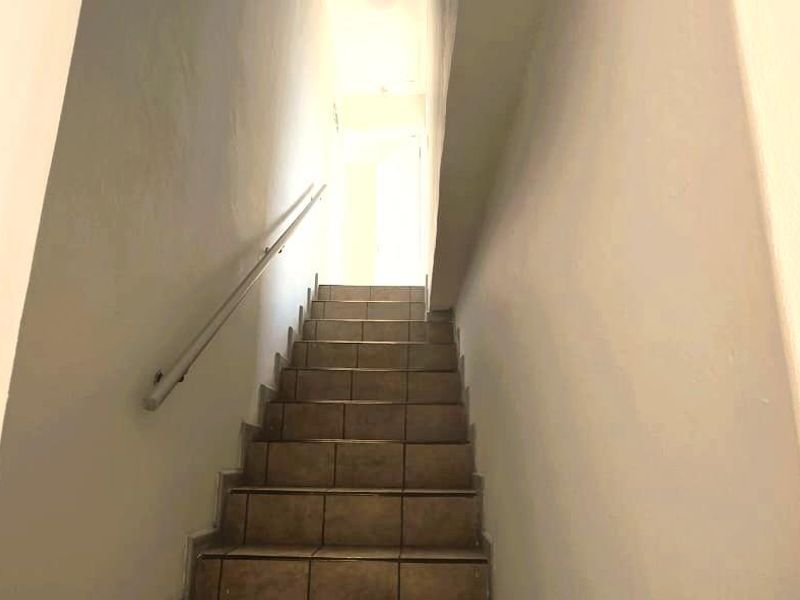 A functional staircase with tiled steps and a wall-mounted handrail leading to an upper level.