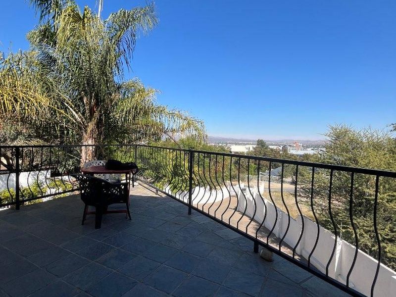 An elevated balcony featuring stone tile flooring and a wrought iron railing, offering expansive outdoor views.