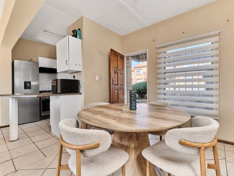 Open-plan kitchen and dining area featuring tiled flooring, functional cabinetry, and a breakfast bar, with direct access to the exterior.
