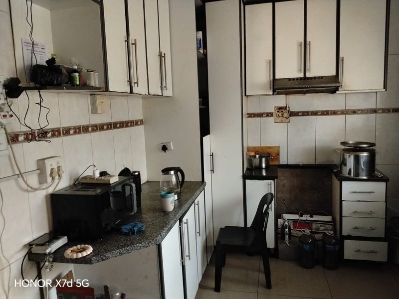 A functional kitchen featuring built-in cabinetry, granite countertops, and a tiled backsplash, currently requiring cosmetic updates and maintenance to improve its overall condition.