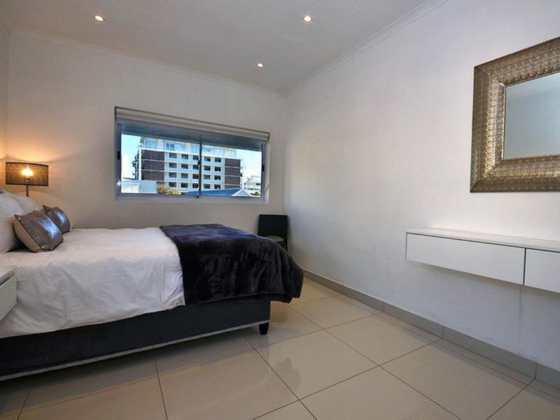 A well-maintained bedroom featuring tiled flooring, recessed downlighting, and a wall-mounted floating vanity unit.