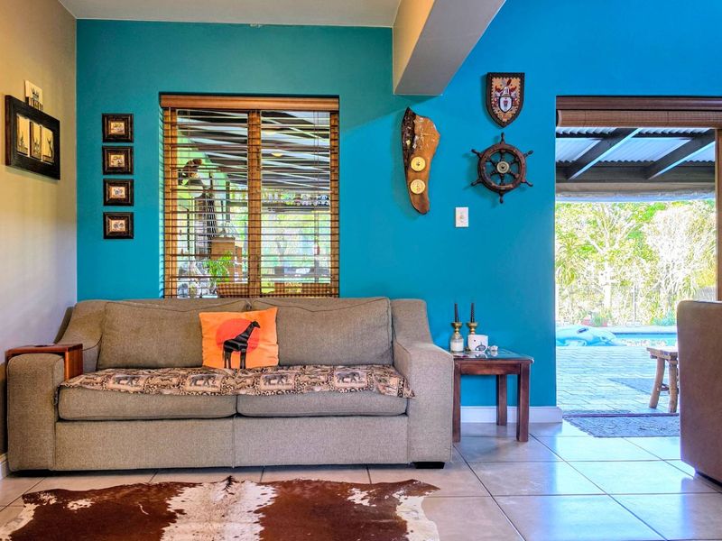 A bright living room featuring vibrant blue accent walls, tiled flooring, and direct access to an outdoor patio area through a sliding glass door.