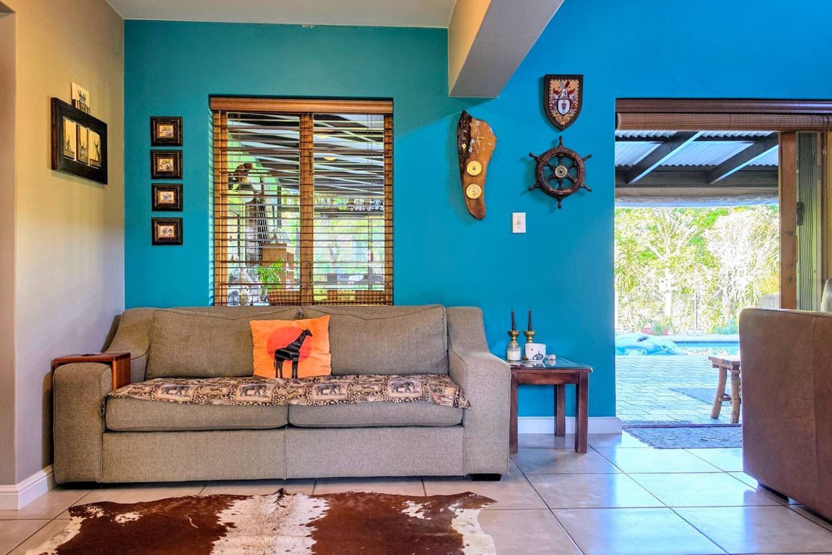 A bright living room featuring vibrant blue accent walls, tiled flooring, and direct access to an outdoor patio area through a sliding glass door.