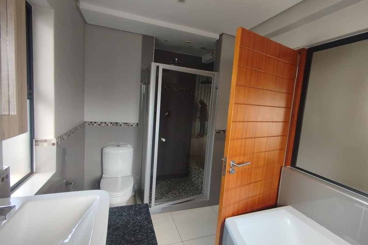 Modern bathroom featuring a shower enclosure, toilet, and vanity basin with granite countertop, finished with neutral wall tiles and floor tiling.