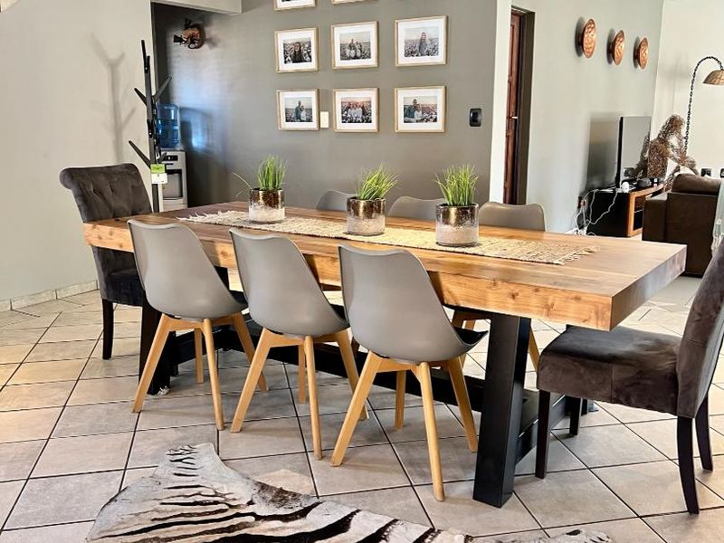 A well-lit dining area featuring tiled flooring, a staircase, and neutral wall tones, providing a functional space for family meals and entertaining.