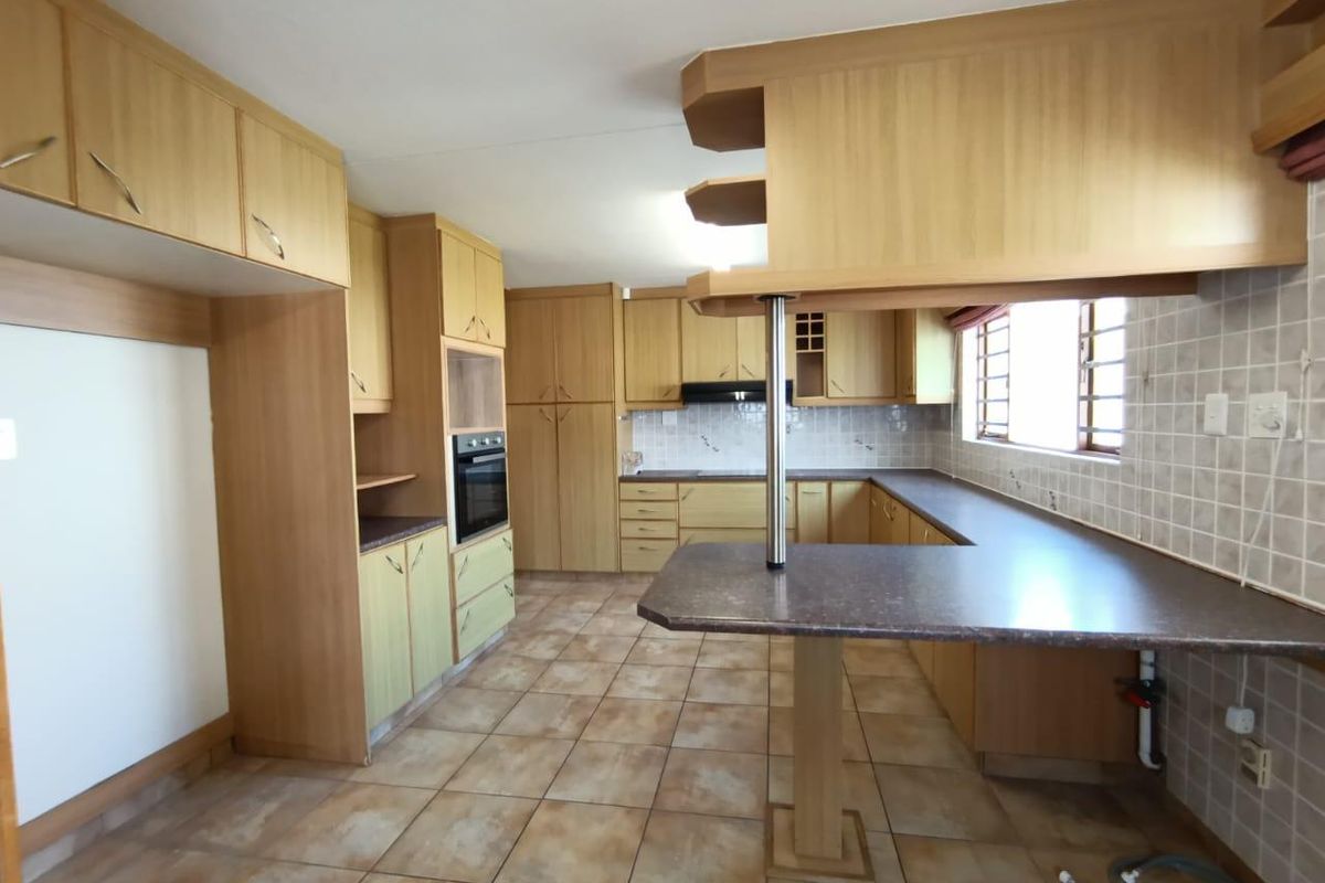 Spacious kitchen featuring extensive built-in cabinetry, laminate countertops, a breakfast bar, built-in oven, and tiled flooring throughout.