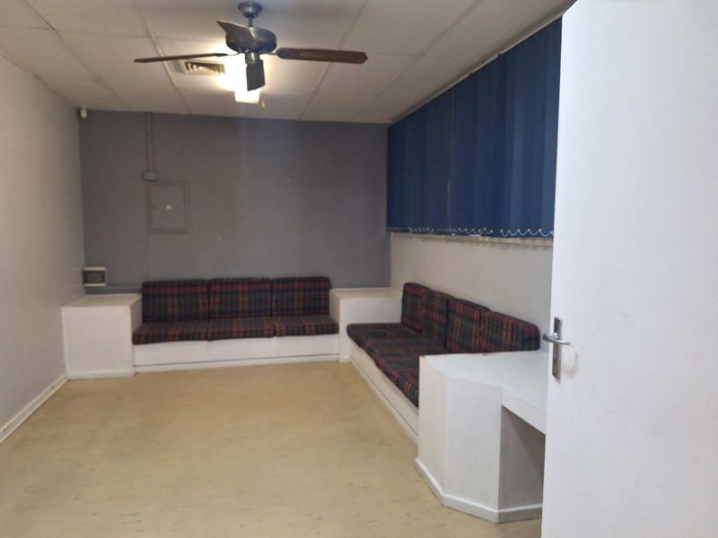 Office space featuring built-in seating, a ceiling fan, and vertical blinds, offering a functional layout with potential for modernization.