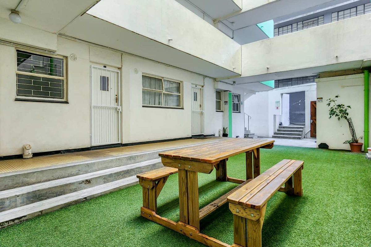 Communal courtyard area featuring artificial turf, concrete steps, and access to apartment units with security gates.