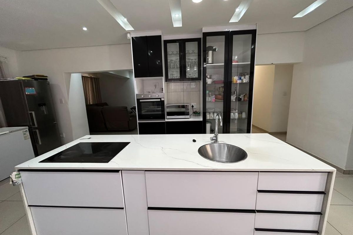 Modern kitchen featuring a central island with an integrated hob and sink, complemented by sleek cabinetry and built-in appliances.