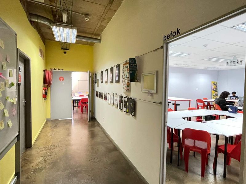 A functional office hallway with polished concrete floors, exposed industrial ceiling, and access to multiple workspace rooms.