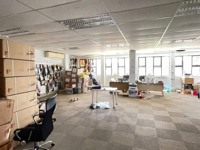Open-plan office space featuring suspended ceilings, recessed lighting, wall-mounted air conditioning, and large windows providing natural light.