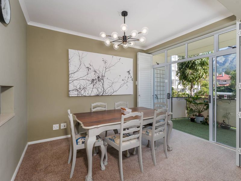 Dining area featuring carpet flooring, a modern chandelier, and large sliding glass doors providing access to a private balcony.