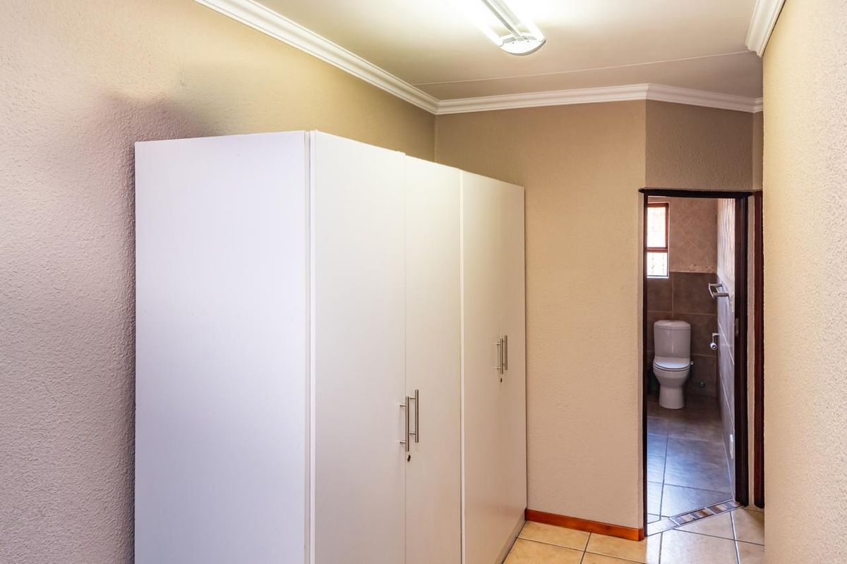 Bedroom featuring built-in cupboards, tiled flooring, and direct access to an en-suite bathroom.