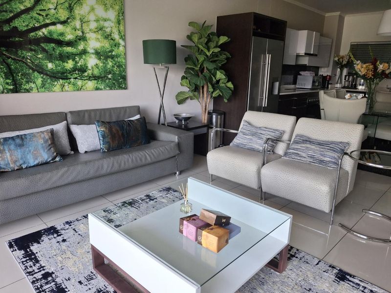 An open-plan living and kitchen area featuring tiled floors, modern cabinetry, and a functional layout suitable for contemporary apartment living.