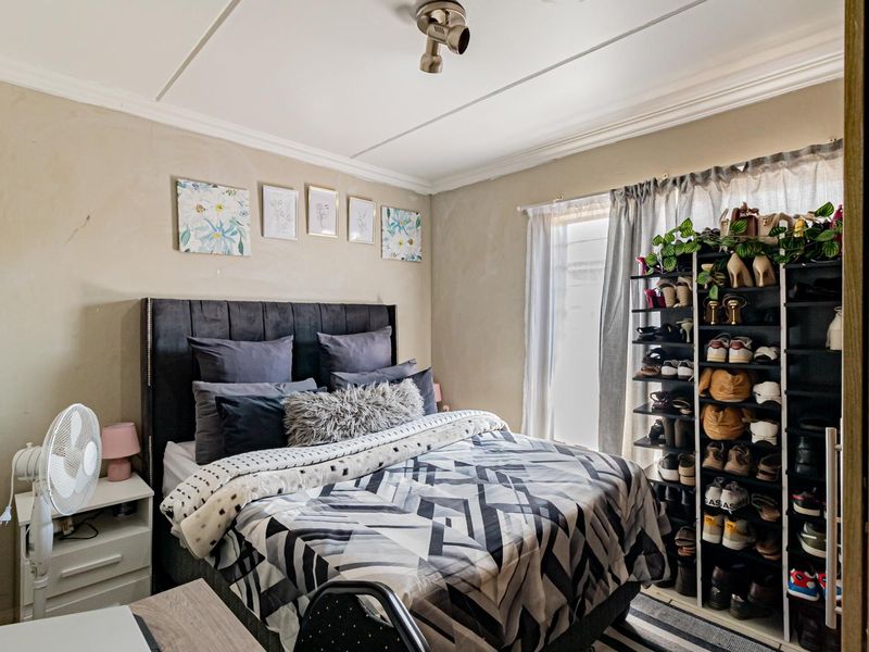 A well-lit bedroom featuring neutral wall tones, a ceiling-mounted spotlight, and classic cornice detailing, providing a comfortable and functional living space.