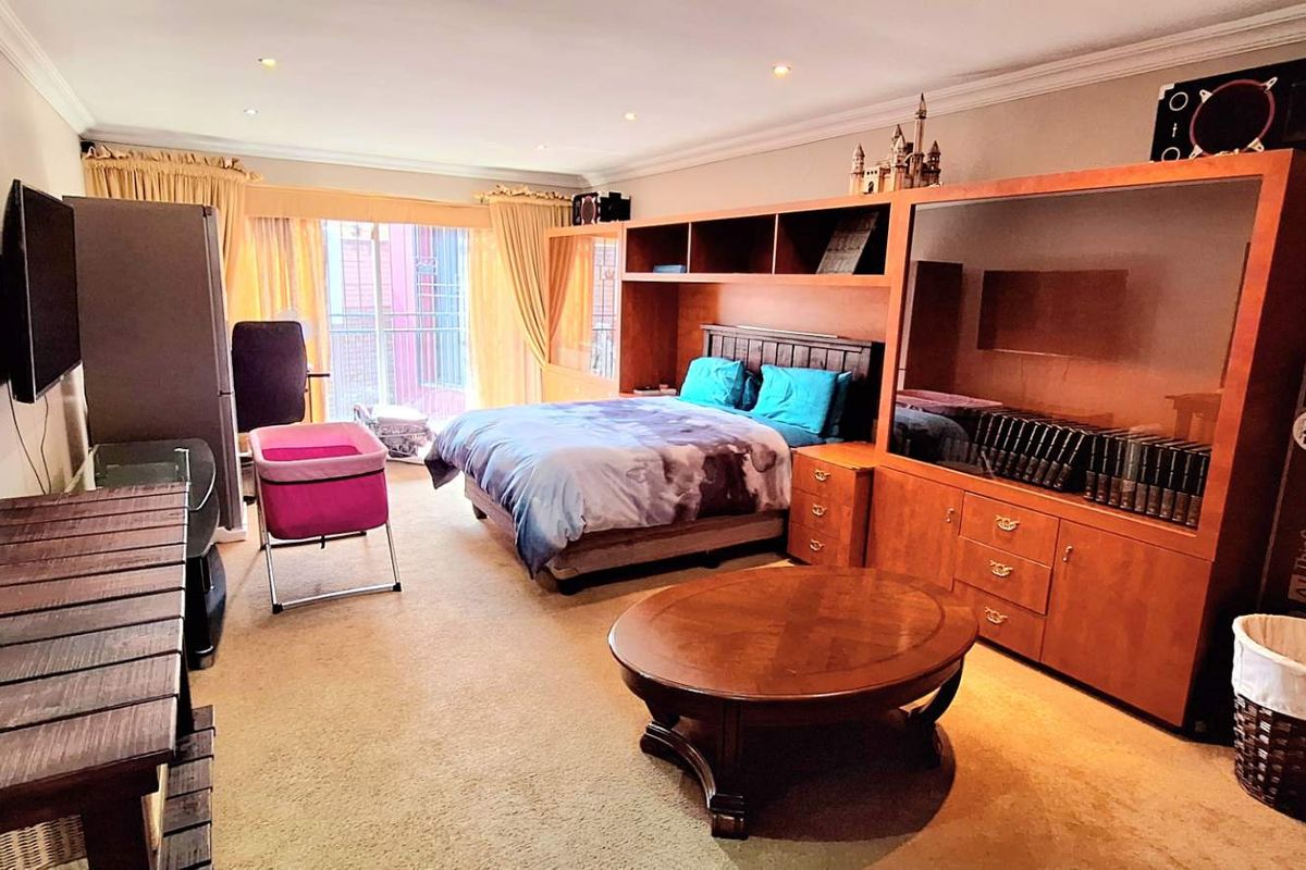 Spacious bedroom featuring built-in wooden cabinetry, recessed ceiling lighting, and sliding door access to a private balcony.