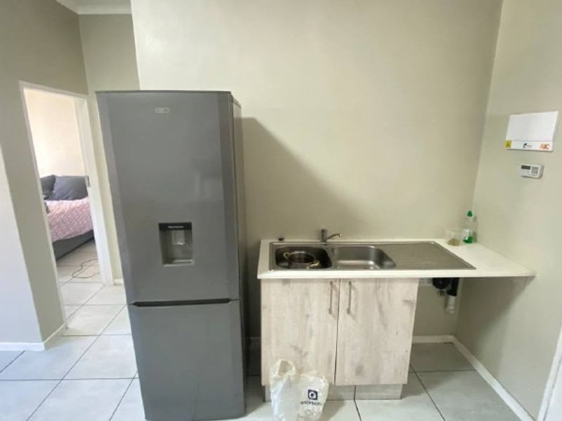 A functional scullery area featuring a stainless steel sink, built-in base cabinetry, and tiled flooring, providing a practical utility space.