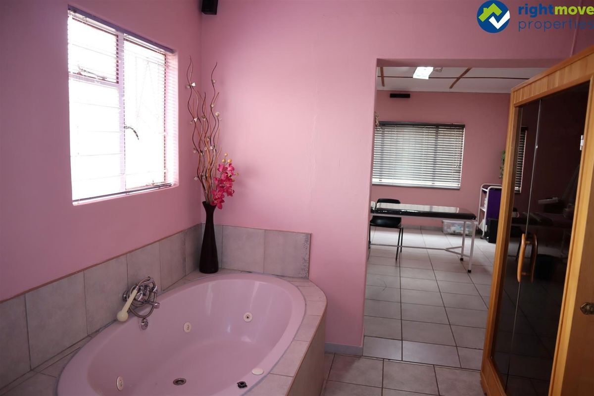 A treatment room featuring a built-in jetted bathtub with tiled surround, leading into an adjacent office or therapy space with tiled flooring.