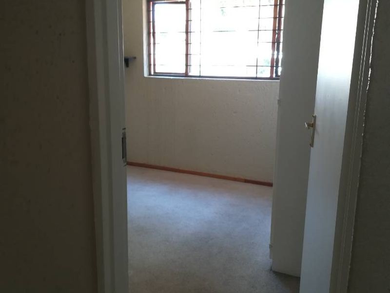 An empty bedroom featuring carpeted flooring and security bars on the window, requiring cosmetic updates to improve its overall condition.