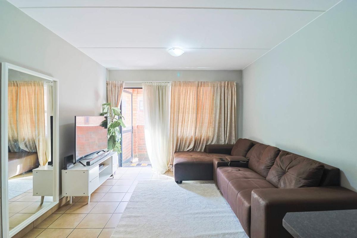 A living room featuring tiled flooring and a sliding glass door providing access to an outdoor balcony area.