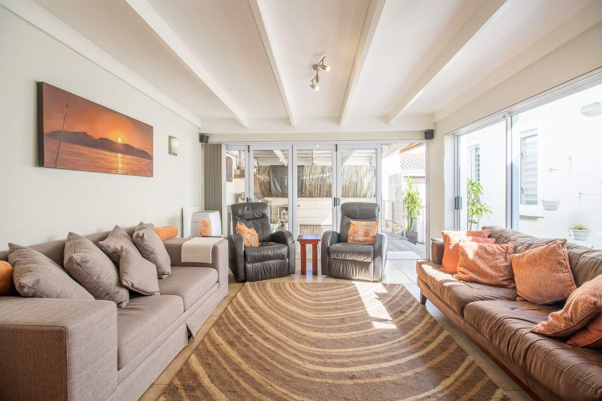 Bright living room featuring exposed beam ceilings and large sliding glass doors that provide seamless access to the outdoor patio area.