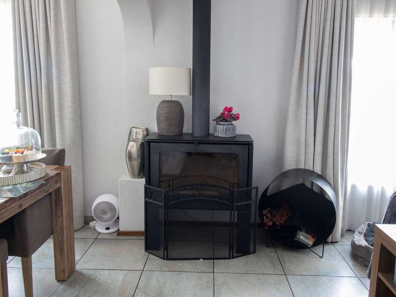 A cozy living area featuring a prominent black freestanding fireplace, tiled flooring, and an architectural archway, creating a warm and inviting atmosphere.