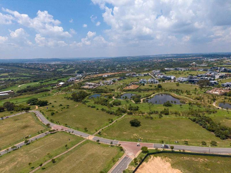 An aerial view of a residential estate featuring paved roads, landscaped green spaces, and water features within a developed community.