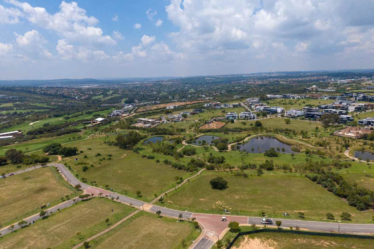 An aerial view of a residential estate featuring paved roads, landscaped green spaces, and water features within a developed community.