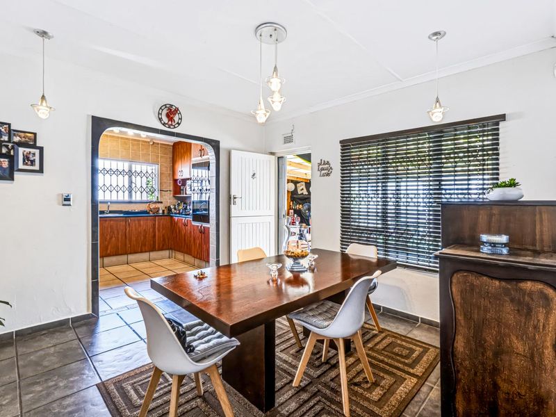 Open plan dining area featuring tiled floors, pendant lighting, and an arched transition into the adjacent kitchen space.