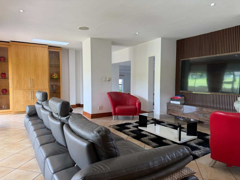 Spacious living room featuring a slatted timber feature wall, built-in cabinetry, recessed downlights, and tiled flooring.