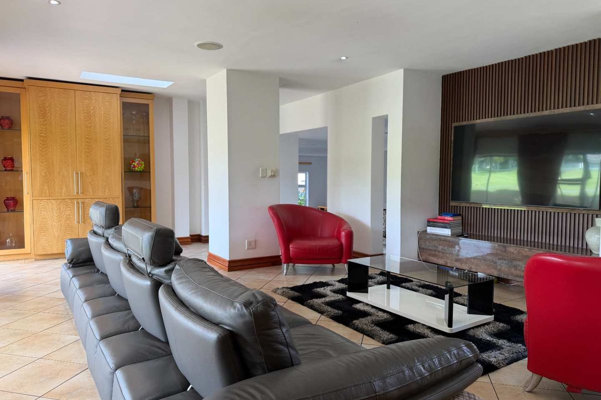 Spacious living room featuring a slatted timber feature wall, built-in cabinetry, recessed downlights, and tiled flooring.