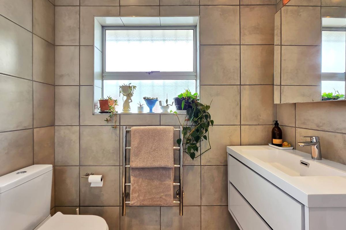 A modern bathroom featuring a wall-mounted vanity with integrated basin, chrome fixtures, a heated towel rail, and neutral wall tiling.