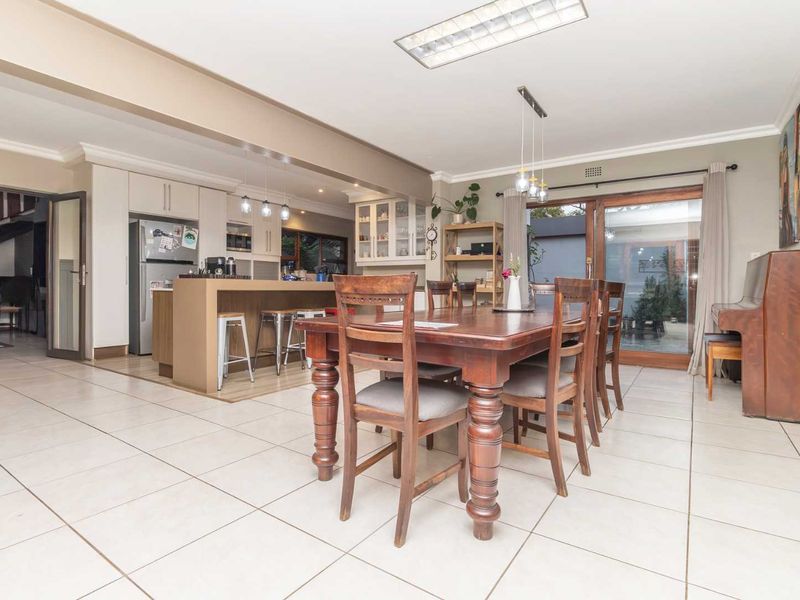 Spacious open-plan living and dining area featuring a modern kitchen with island, tiled floors, and large sliding doors leading to the outdoor space.