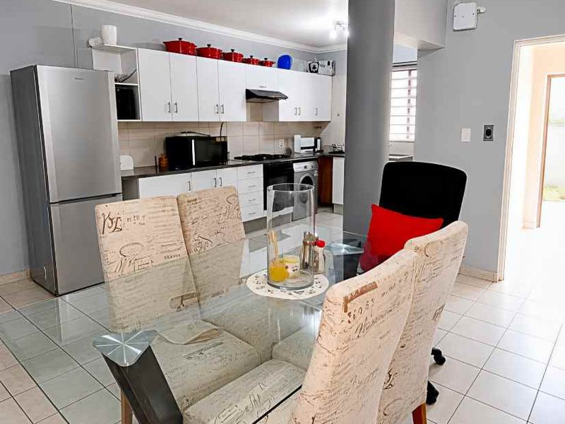 Open-plan kitchen and dining area featuring white cabinetry, tiled flooring, and a central structural column, creating a functional living space.