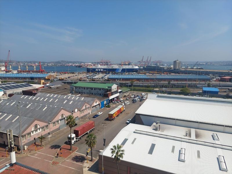 Elevated view overlooking the industrial harbour area, featuring shipping infrastructure, warehouses, and surrounding urban landscape.