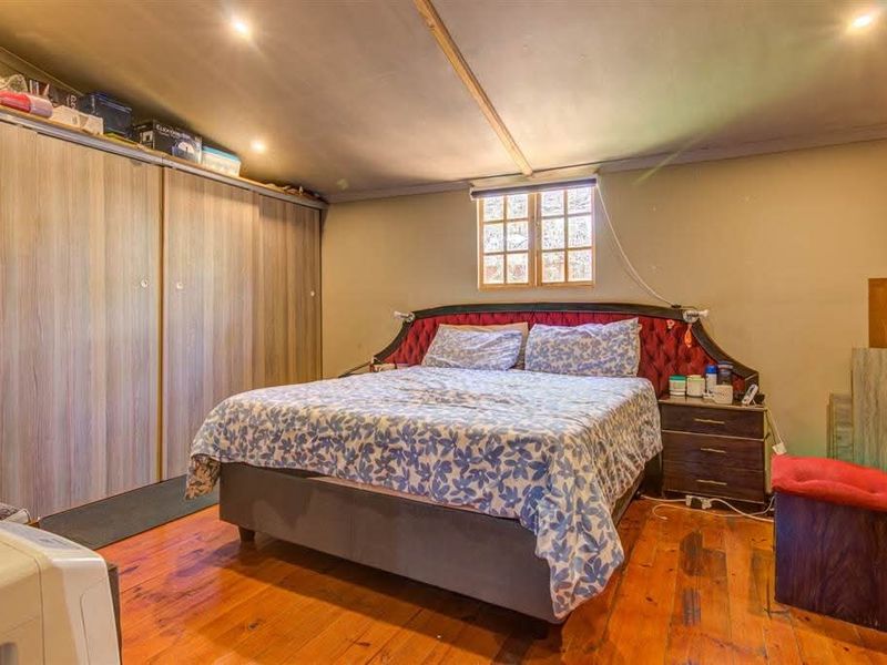 A bedroom featuring timber flooring, built-in cupboards, and recessed downlighting.