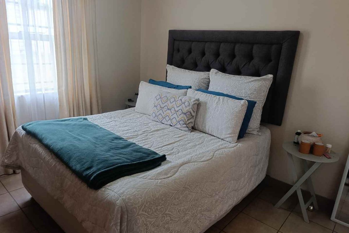A well-lit bedroom featuring tiled flooring and neutral wall tones, providing a comfortable and functional living space.