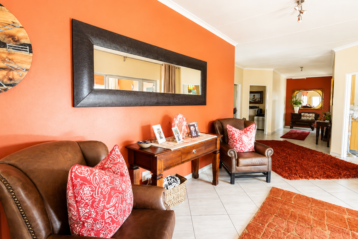 A spacious living area featuring tiled flooring and coved ceilings, with an open layout leading into adjacent rooms.
