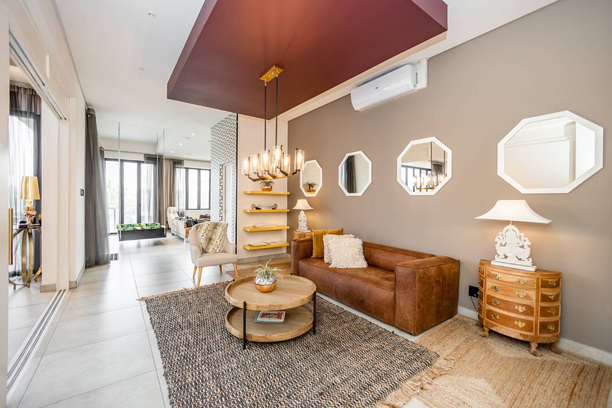 A modern living room featuring tiled flooring, a recessed ceiling detail with pendant lighting, and a wall-mounted air conditioning unit.