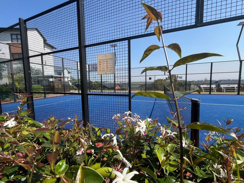 A well-maintained outdoor padel court featuring synthetic turf, secure perimeter fencing, and integrated court lighting within the apartment complex.