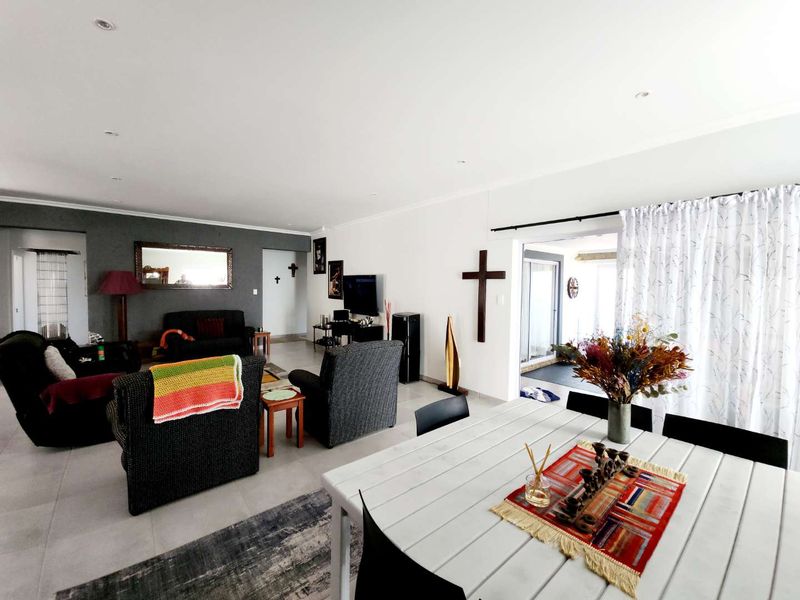 Spacious open-plan living and dining area featuring neutral tiled flooring, recessed lighting, and direct access to an adjoining patio through sliding glass doors.