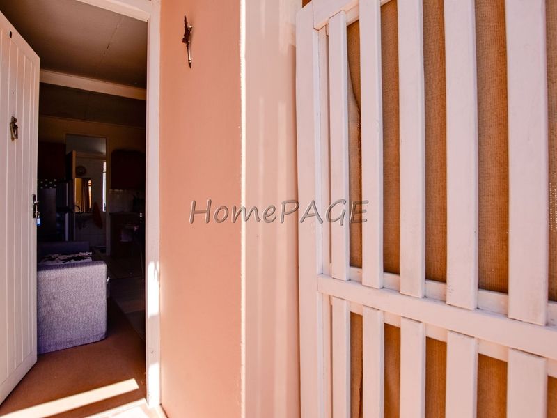 Entrance view showing a white security gate and main door leading into the interior living space.
