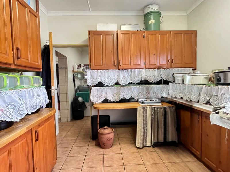 A dated kitchen featuring traditional wooden cabinetry, tiled flooring, and laminate countertops, offering significant potential for a modern renovation.